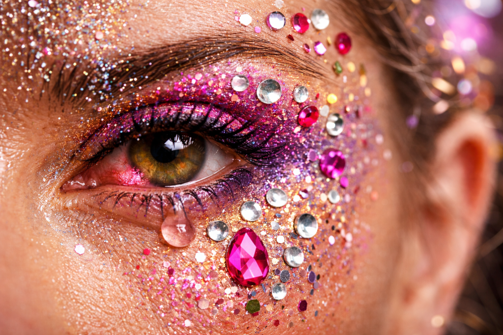 Maquiagem de carnaval com glitter e strass, destacando os riscos para a saúde dos olhos.