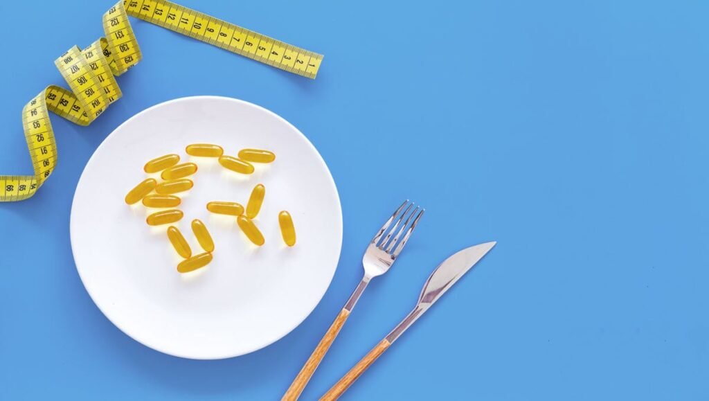 Vários frascos de medicamentos para emagrecimento sobre uma mesa, com frutas e vegetais ao fundo