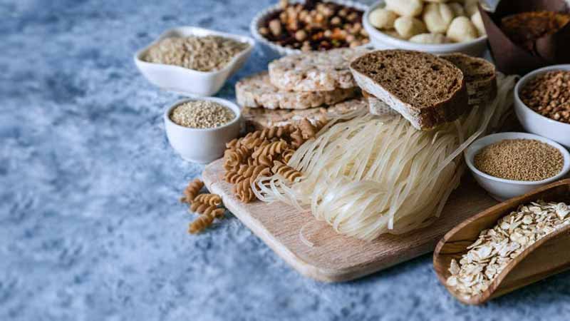 Pessoa segurando alimentos sem glúten, simbolizando a dieta para Doença Celíaca