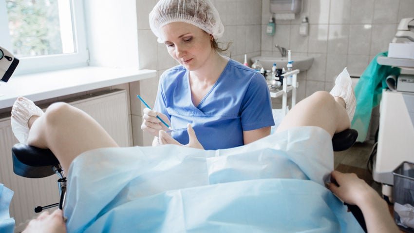 Mulher passando por exame Papanicolau em consultório médico