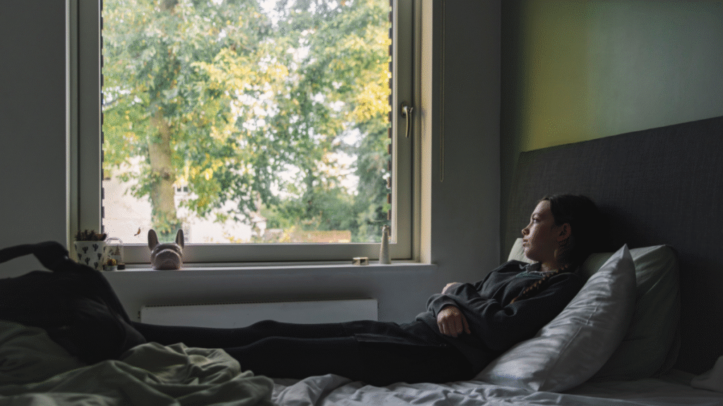 Uma jovem sentada em um quarto escuro, cercada por dispositivos eletrônicos, simbolizando o isolamento social e o hikikomori.