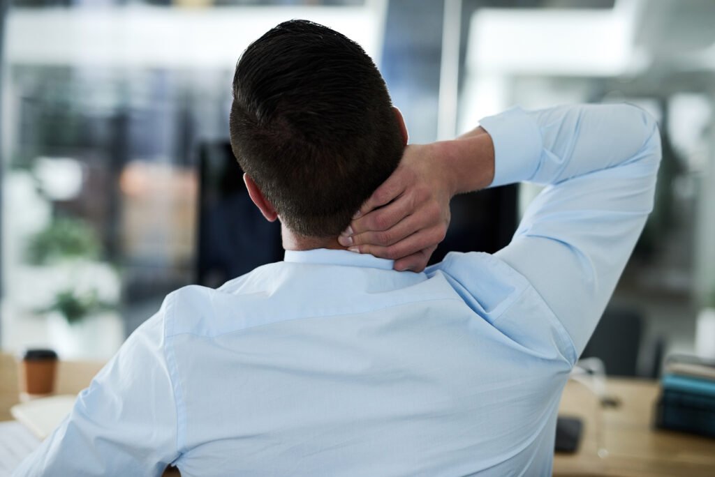 Trabalhador ajustando sua mesa para uma postura ergonômica adequada no ambiente de trabalho.